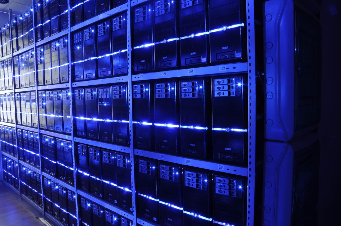 An engineer walking between rows of servers in a data center checking systems and cabling.